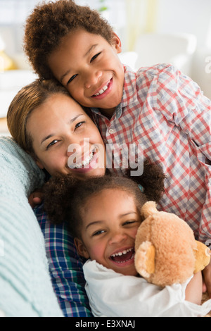 Mère et enfants sourire noir sur canapé Banque D'Images