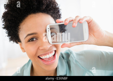 Black woman holding photo de son oeil sur son visage Banque D'Images