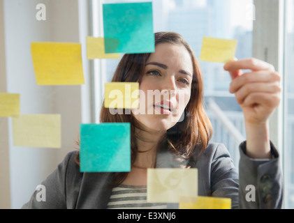 Businesswoman reading notes adhésives sur verre Banque D'Images