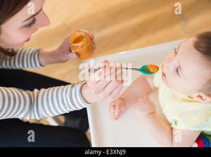 Mère nourrir bébé dans une chaise haute Banque D'Images