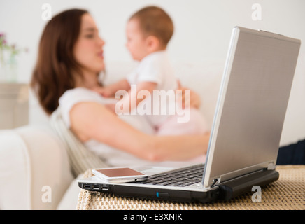 Ordinateur portable et téléphone cellulaire à côté de mère avec bébé Banque D'Images