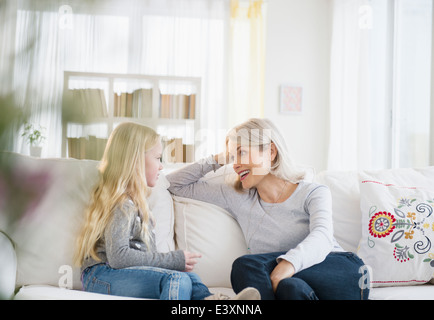 Woman and granddaughter en conversation sur canapé Banque D'Images