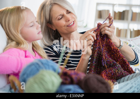 Woman and granddaughter knitting sur canapé Banque D'Images