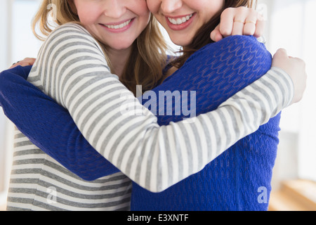 Women hugging in living room Banque D'Images