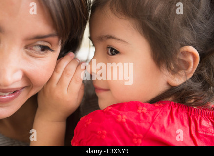 Hispanic girl whispering in mother's ear Banque D'Images