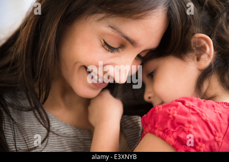 Hispanic girl whispering in mother's ear Banque D'Images