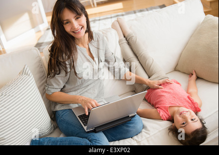 Hispanic mother and daughter relaxing on sofa Banque D'Images