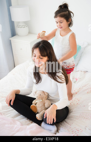 Hispanic girl brushing mother's hair Banque D'Images