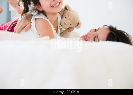Hispanic mother and daughter relaxing on bed Banque D'Images