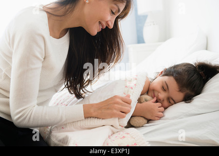 Mère fille hispanique rentrant dans le lit Banque D'Images