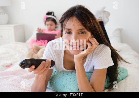 Hispanic mother and daughter relaxing on bed Banque D'Images