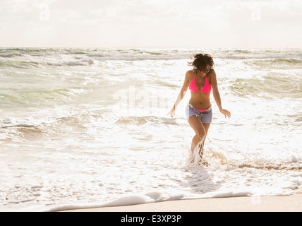 African American Woman playing in waves on beach Banque D'Images