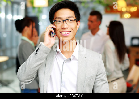 Happy asian businessman talking on smartphone le devant des collègues Banque D'Images