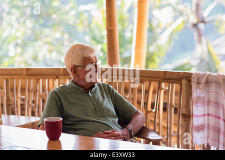 Caucasian man ayant tasse de café en treehouse Banque D'Images