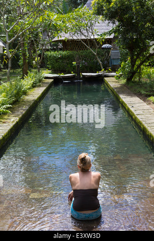 Caucasian woman sitting in piscine moderne Banque D'Images