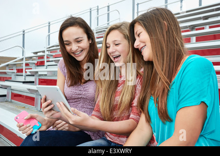 Teenage Girls using digital tablet in gradins Banque D'Images