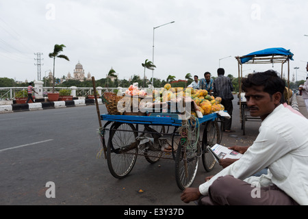 Vendeur papaye détente sur un trottoir à Hyderabad, Inde Banque D'Images