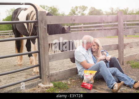 Couple contre clôture et un cheval curieux Banque D'Images