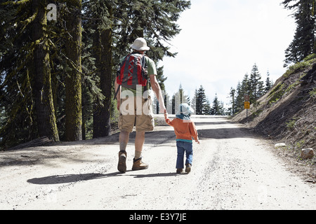 Vue arrière du père et fille, main dans la main marcher à travers la forêt de l'Oregon, USA Banque D'Images