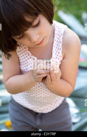 Girl holding et à la recherche à l'anole vert lézard dans jardin Banque D'Images