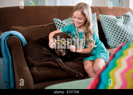 Girl holding sunglasses sur chien labrador de couleur chocolat réticents Banque D'Images