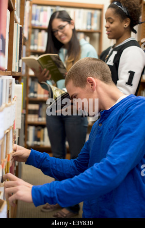 Les étudiants choisissant books in library Banque D'Images