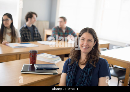 Teacher sitting at desk, portrait Banque D'Images