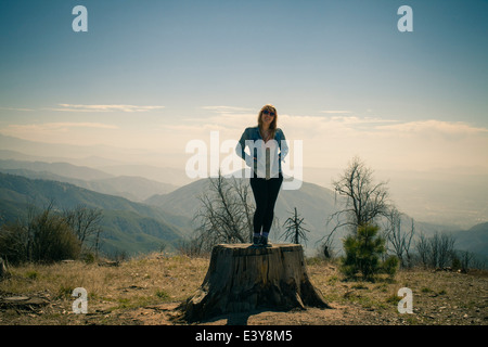 Portrait of mid adult woman sitting on tree trunk, Lake Arrowhead, California, USA Banque D'Images