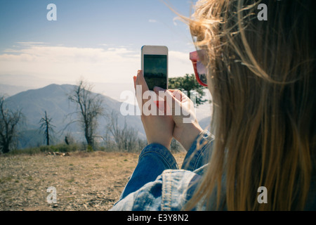 Cropped shot of mid adult woman photographing view sur smartphone, Lake Arrowhead, California, USA Banque D'Images