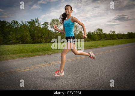 Teenage girl running on road Banque D'Images