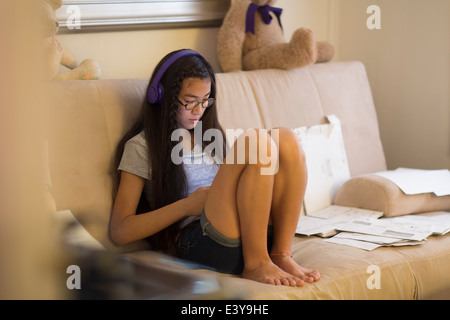 Teenage girl sitting on sofa, portant des écouteurs Banque D'Images