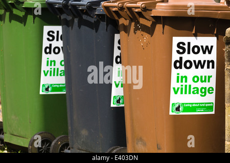 Ralentir dans notre village' ; enseignes fixées au conseil local poubelles de recyclage. Le Norfolk. UK Banque D'Images