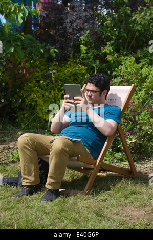 Homme assis dans une chaise longue à l'aide de l'ipad au Hay Festival 2014 ©Jeff Morgan Banque D'Images