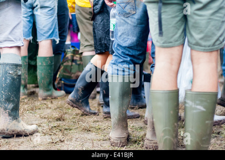 Festivaliers profitez d'un groupe à l'étape de la pyramide à Glastonbury Festival 2014, portant ses bottes dans la boue Banque D'Images