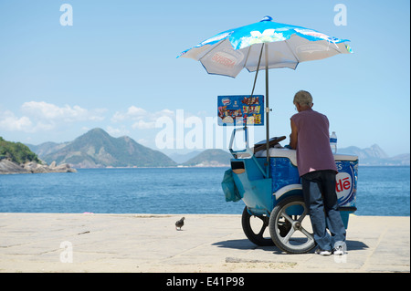 RIO DE JANEIRO, Brésil - 11 février 2014 : Brésilien vendeur vend de la crème glacée se dresse à l'entrée de plage rouge à Urca Banque D'Images