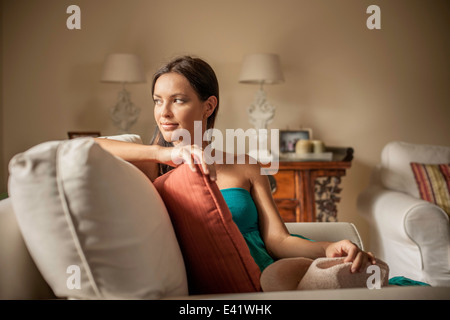 Jeune femme contemplative sitting in armchair Banque D'Images