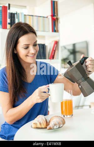 Young woman pouring coffee pour le petit déjeuner Banque D'Images