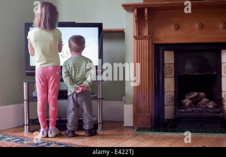 Vue arrière de soeur et frère debout trop près et regarder la télévision Banque D'Images