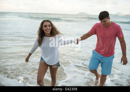 Jeune couple paddling in sea, la plage d'Ipanema, Rio de Janeiro, Brésil Banque D'Images