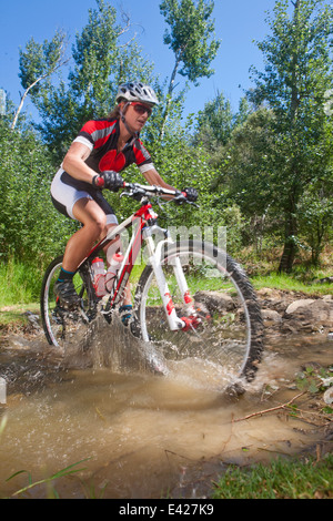 Cycliste féminine équitation à travers stream Banque D'Images