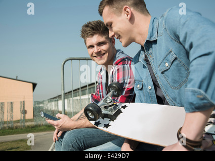 Les jeunes hommes en skatepark, using smartphone Banque D'Images