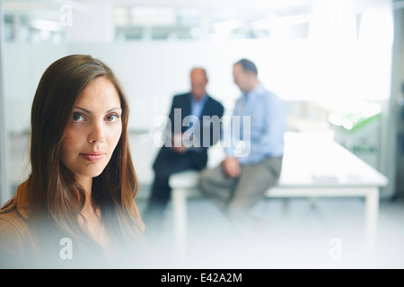 Woman posing for camera, hommes d'affaires en arrière-plan Banque D'Images