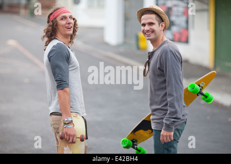 Portrait de deux hommes adultes amis avec skateboards on city street Banque D'Images