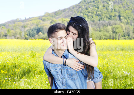 Young couple in field, man giving woman piggy back Banque D'Images