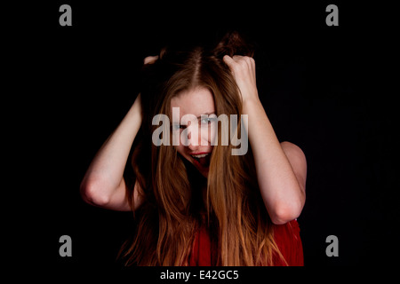 Jeune femme blonde photographiée en studio hurlant de frustration Banque D'Images