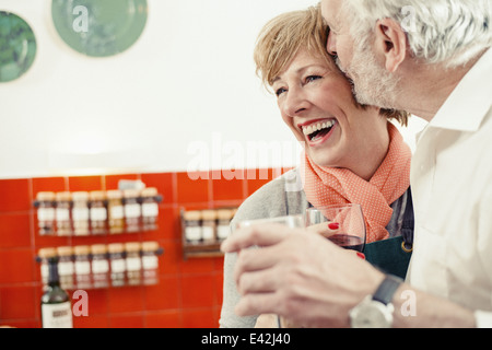 Man kissing woman in kitchen, woman laughing Banque D'Images