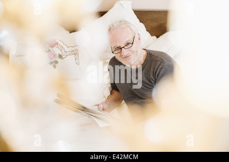 Senior man reading newspaper, smiling Banque D'Images