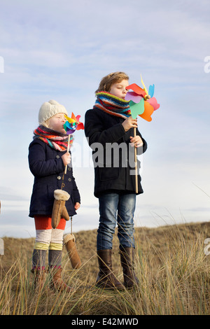 Frère et soeur souffle sur les moulins à papier coast Banque D'Images