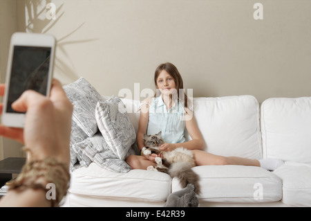Mère fille photographiant avec chat sur canapé Banque D'Images