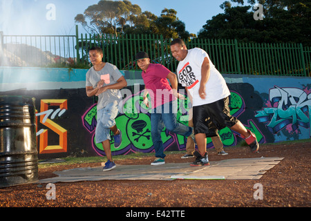 Groupe de quatre hommes en breakdance park at Dusk Banque D'Images